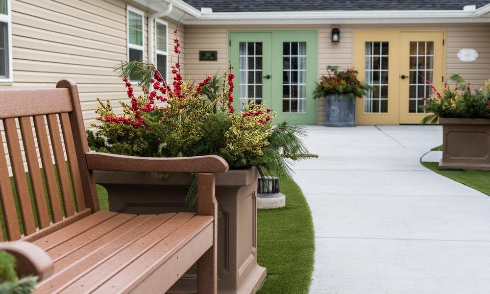 A beautifully landscaped courtyard featuring a bench, vibrant flower arrangements, and colorful doors.