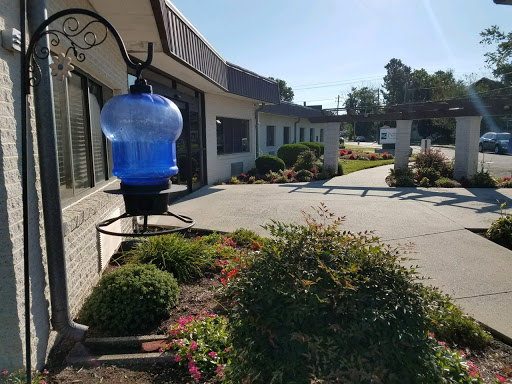 A picturesque view of a building with a blue water container and well-maintained garden on a sunny day.
