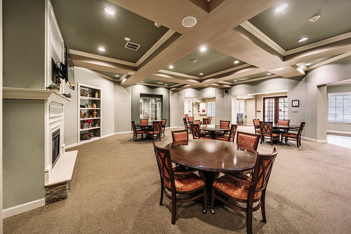 A spacious interior dining area with multiple tables and chairs, featuring elegant lighting and bookshelves.