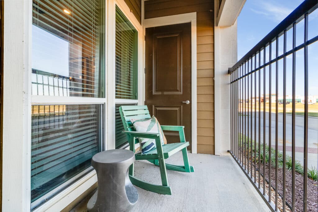 A cozy balcony with a green rocking chair and small side table.