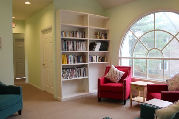 A cozy reading nook with a red armchair and a bookshelf by the window.