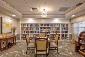 A cozy library room featuring a table and chairs surrounded by bookshelves filled with colorful books.