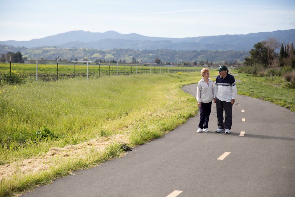 A couple walking together on a scenic path surrounded by nature.