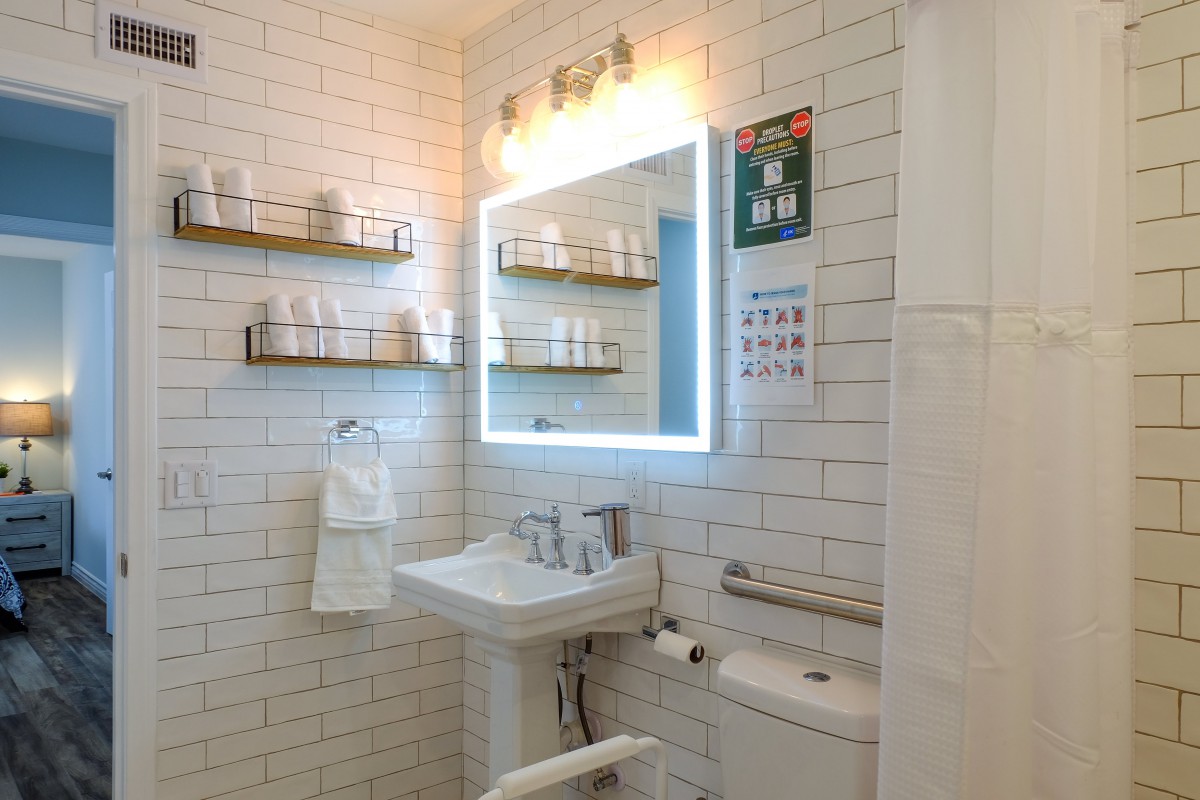A modern bathroom with a well-lit mirror, sink, and organized shelves.