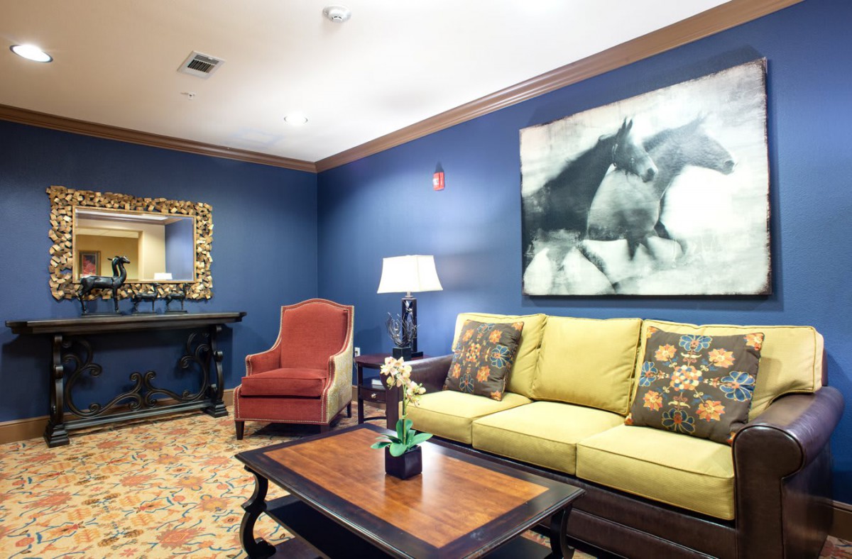 A cozy living room with a yellow sofa, red armchair, and blue walls adorned with artwork and decor.