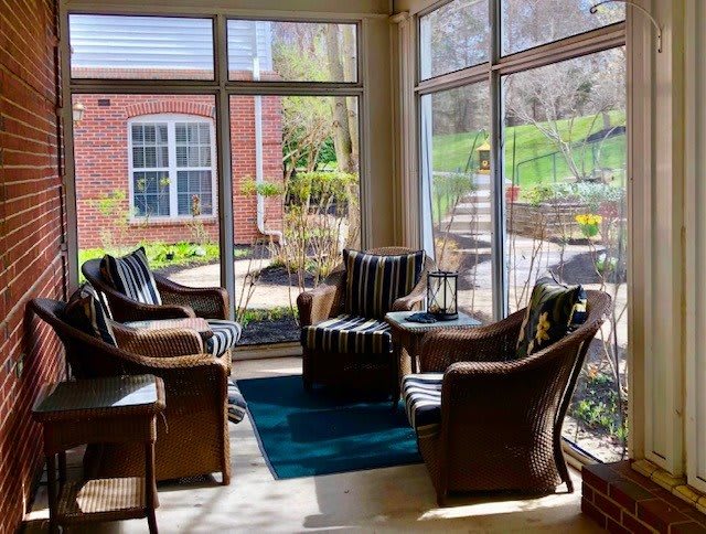 A cozy sunroom with comfortable seating and large windows offering a garden view.