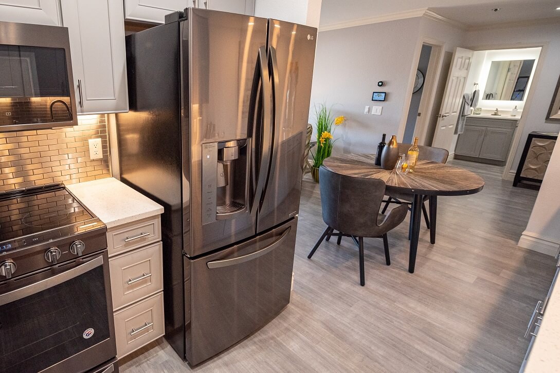 A modern kitchen with a sleek stainless steel refrigerator and a cozy dining area.