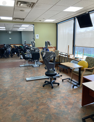 A spacious office area with workstations, chairs, and exercise equipment in the background.