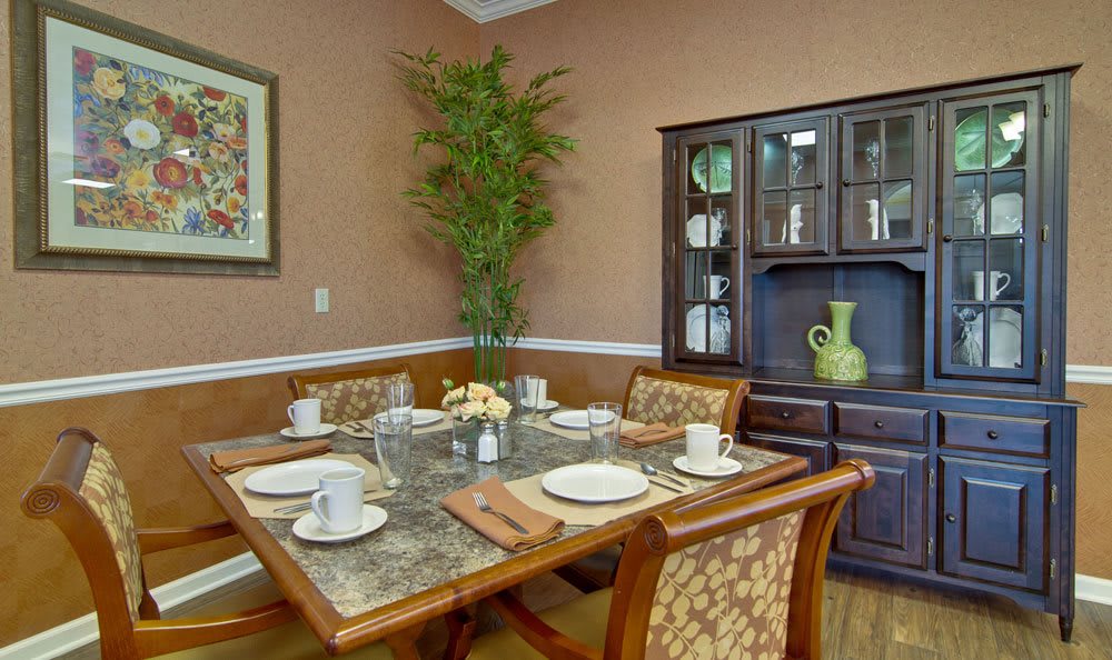 A cozy dining room with a set table, featuring a decorative cabinet and an indoor plant.