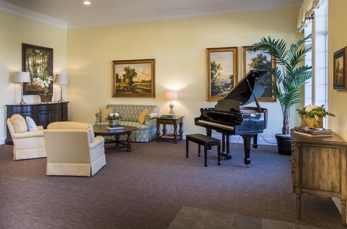 A cozy living room featuring a grand piano, comfortable seating, and decorative artwork.