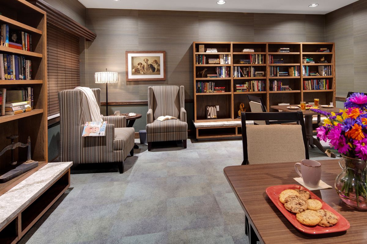 A cozy library space with comfortable armchairs, a table, and well-stocked bookshelves.
