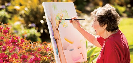A person painting on a canvas outdoors amidst nature.