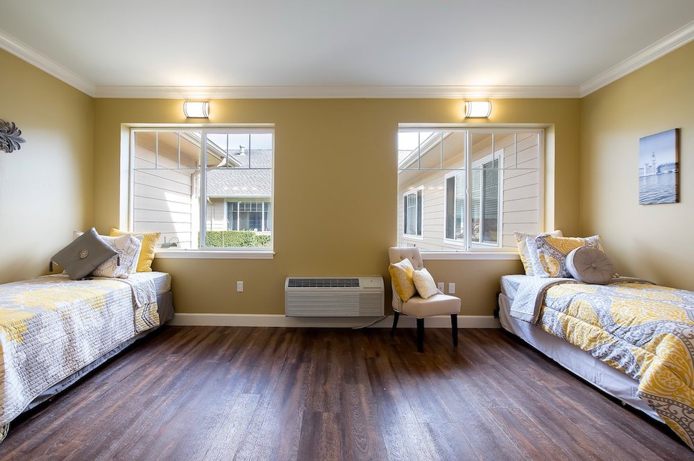 A modern bedroom with two twin beds and ample natural light.