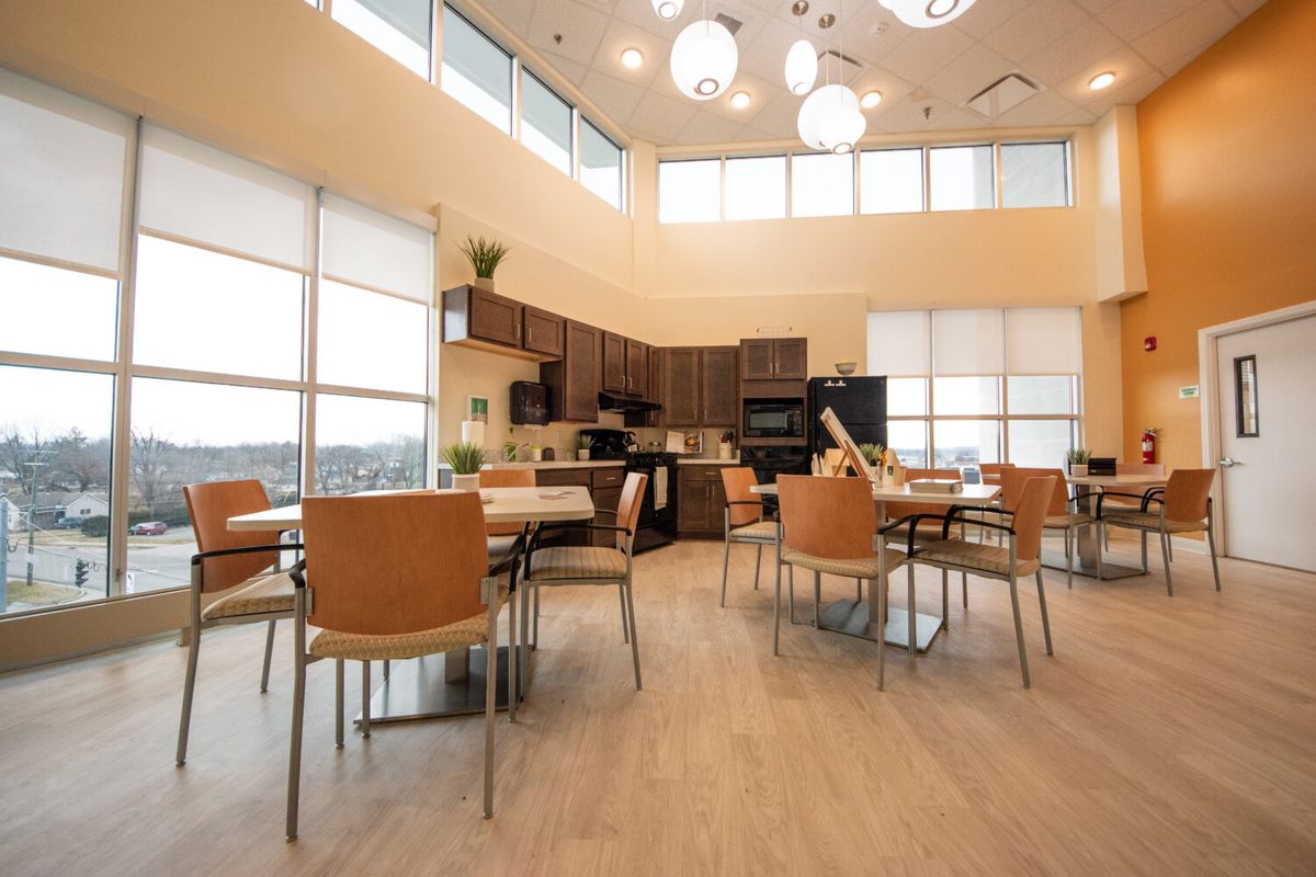 A modern kitchen and dining area with large windows, wooden furniture, and contemporary lighting.