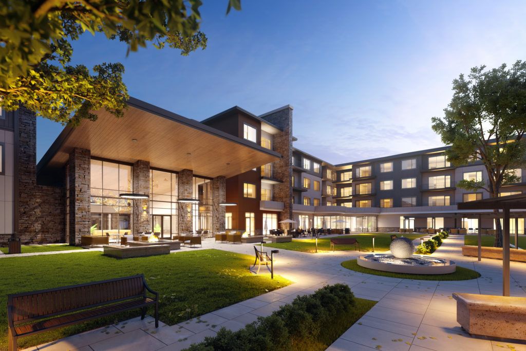 A modern hotel building with illuminated windows and well-maintained landscaping at night.