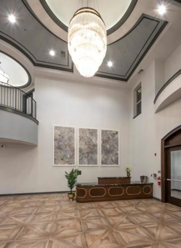 A modern lobby featuring a large chandelier, reception desk, and wall artwork.