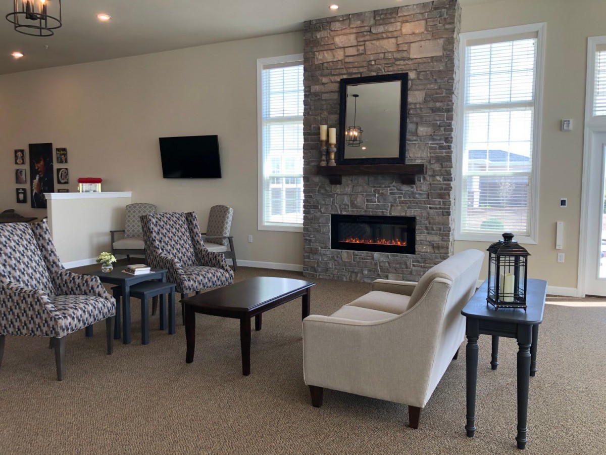 A cozy living room featuring a fireplace, armchairs, a sofa, and a television.