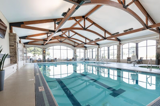 A spacious indoor swimming pool featuring elegant wooden beams and large windows, allowing for plenty of natural light.