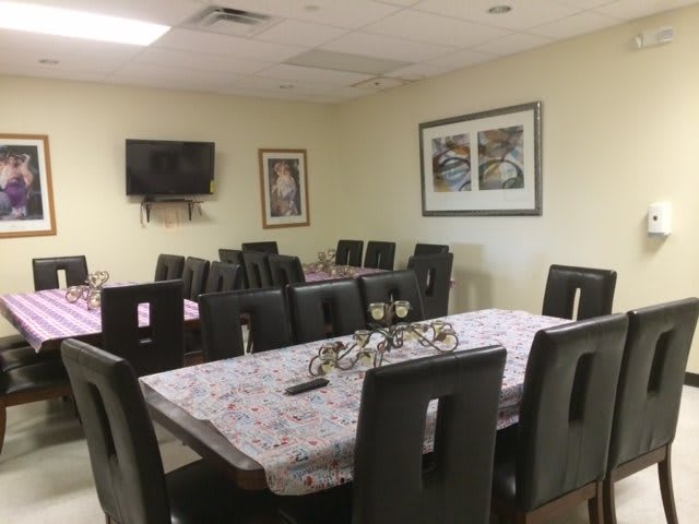 A dining room setup with arranged tables and chairs, featuring wall art and a television.