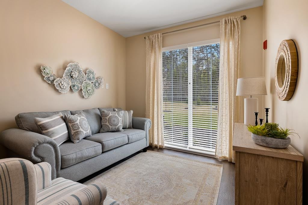 A cozy living room with a comfortable sofa, decorative wall art, and large windows letting in natural light.
