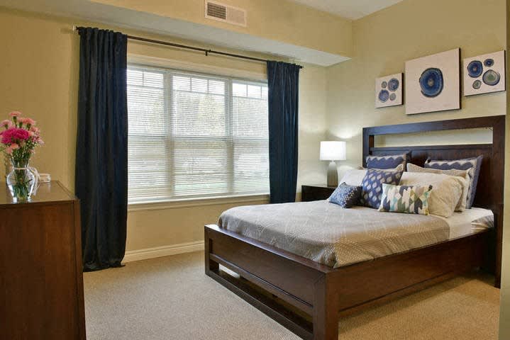 A modern bedroom with elegant furniture and a large window with dark curtains.