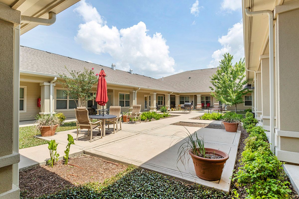 A sunny courtyard with outdoor seating, potted plants, and a well-maintained garden.