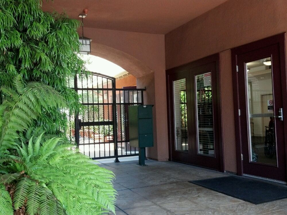 An entrance with a gated archway and lush greenery.