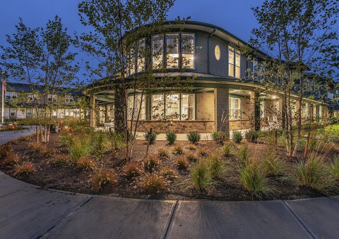 A beautifully lit residential home with modern architecture surrounded by lush landscaping at night.