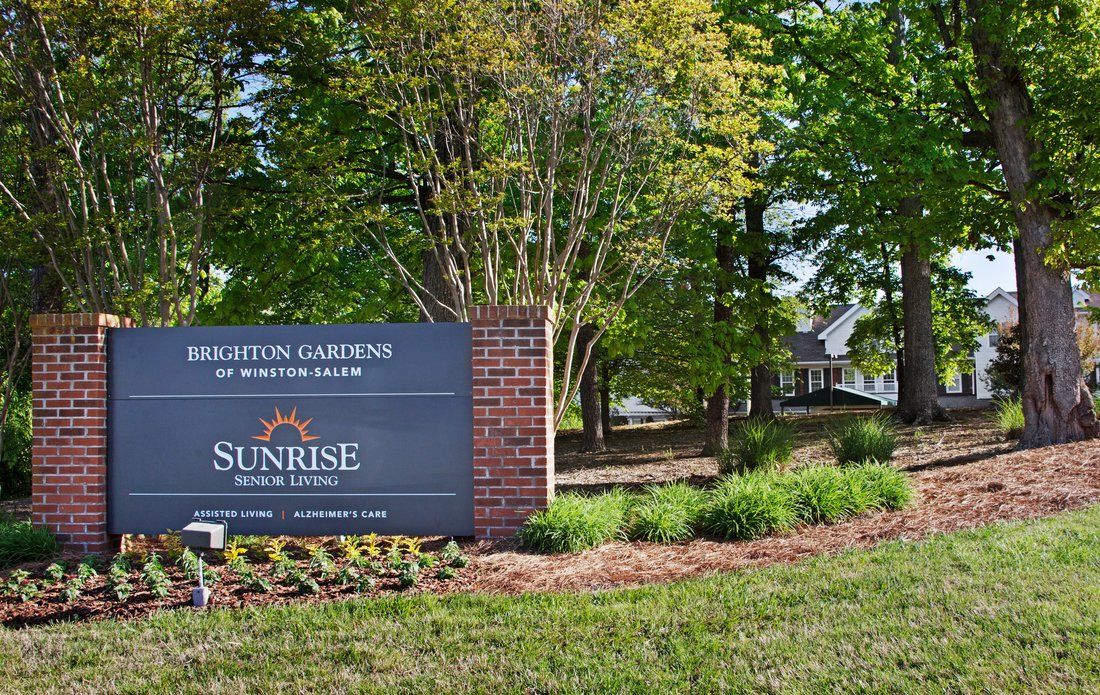 Entrance sign to a building with landscaped surroundings and trees.