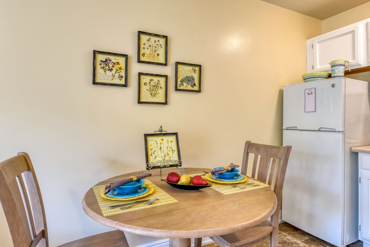 A cozy dining area with a wooden table set for two, featuring colorful plates and utensils.