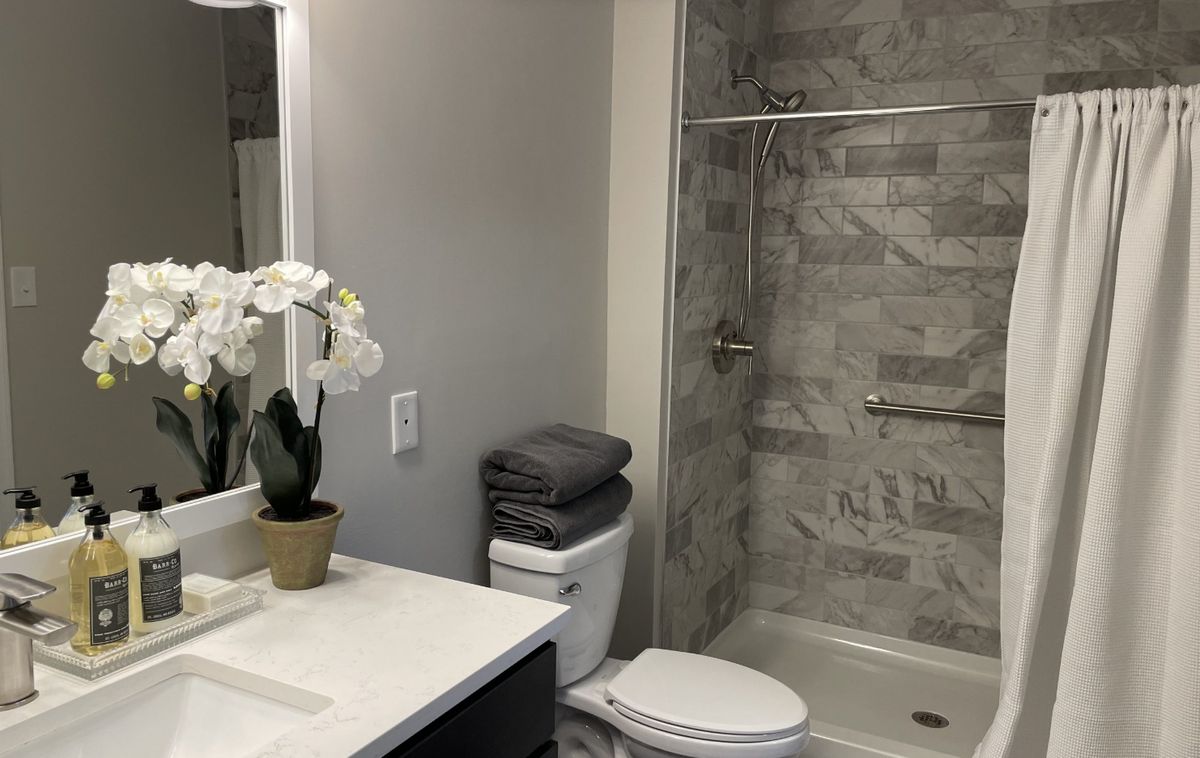 A modern bathroom with a sleek design, featuring gray tiles and an elegant orchid on the countertop.