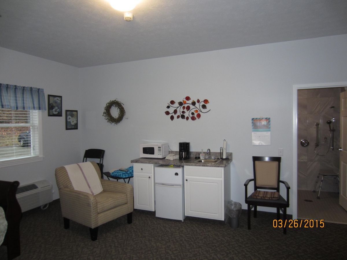 A cozy living room with a kitchenette and simple decor.