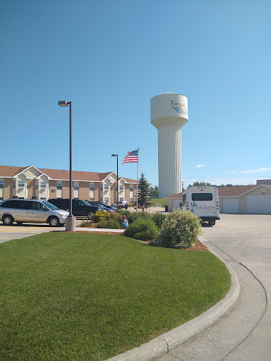 A serene view of a residential area featuring a water tower and an American flag under a clear blue sky.