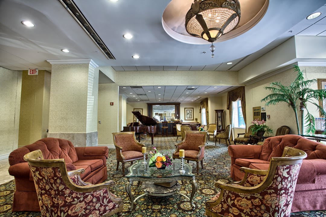 A luxurious hotel lobby featuring elegant seating, a grand piano, and a chandelier.