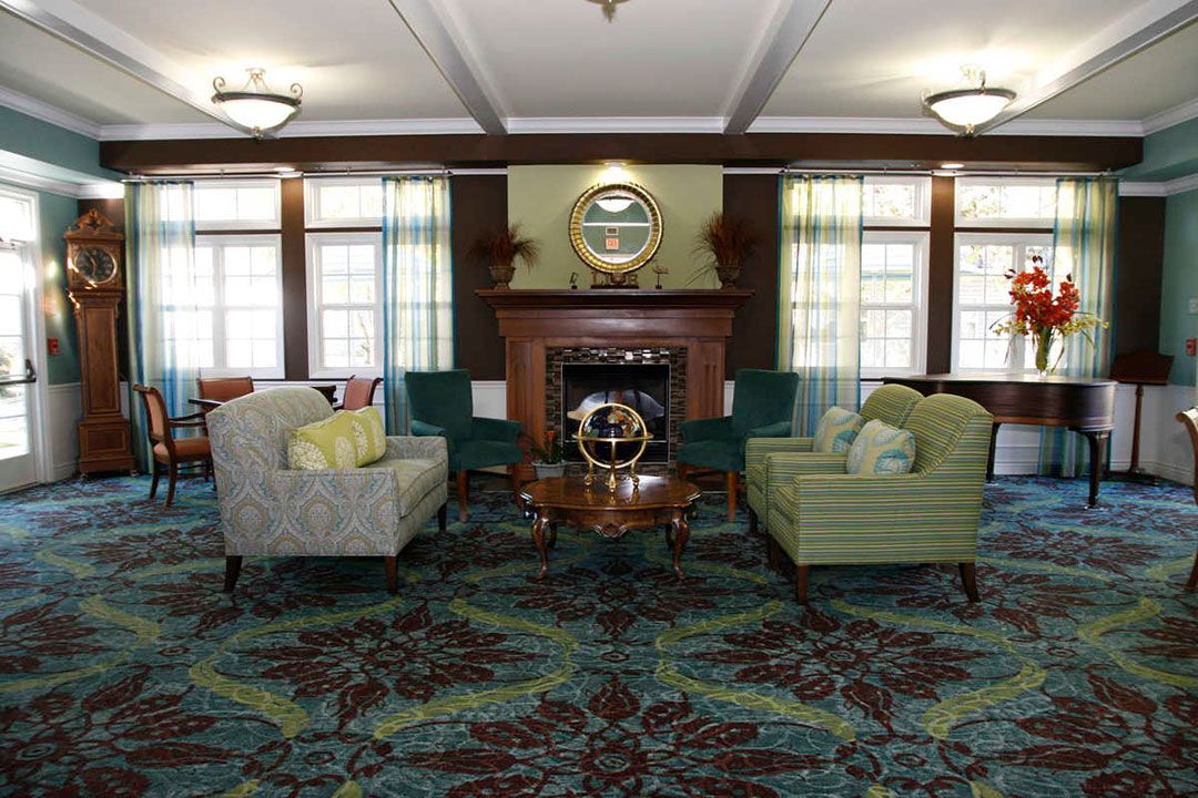 A cozy living room featuring a fireplace, armchairs, and a patterned carpet.