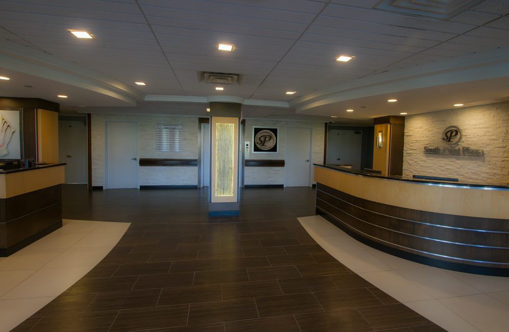 A modern office lobby with a reception desk and overhead lighting.