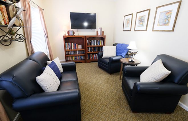 A cozy living room with comfortable seating, bookshelves, and a television.