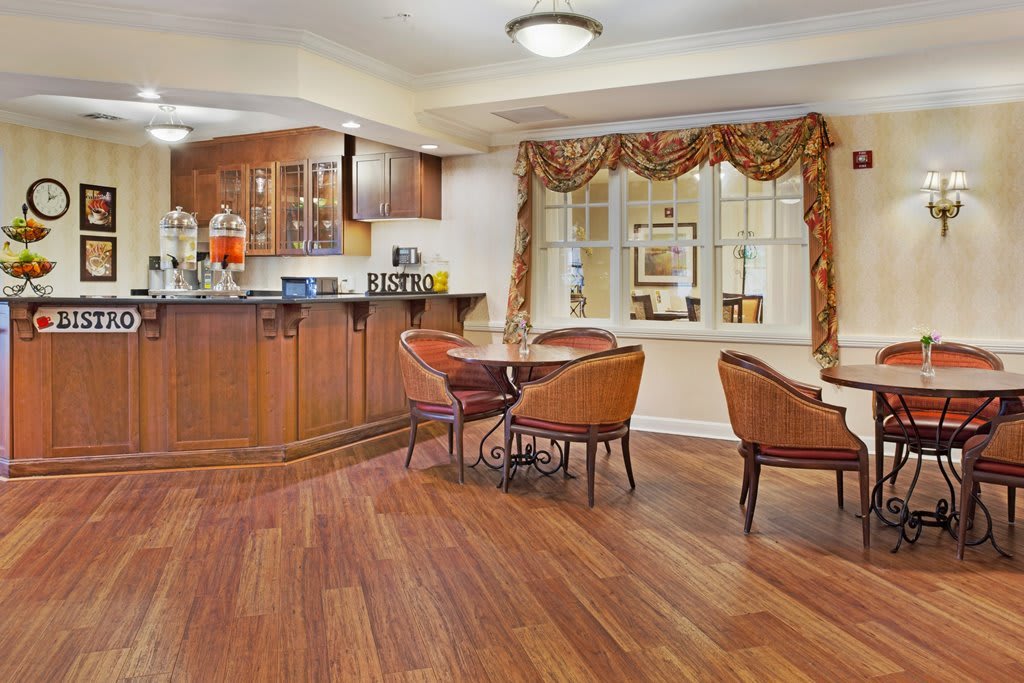 A cozy dining area with a kitchen featuring wooden cabinets and flooring.