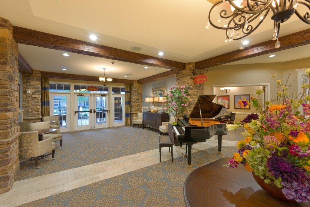 A spacious lobby featuring a grand piano, comfortable seating, and elegant lighting.