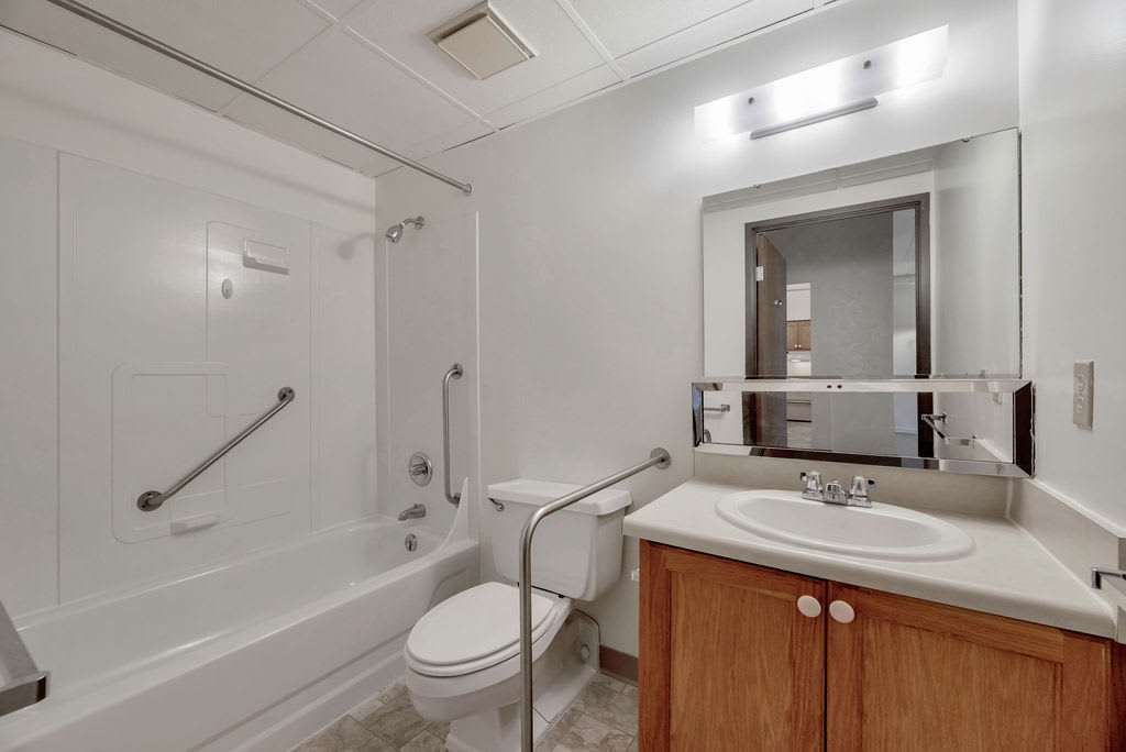 A modern bathroom featuring a bathtub, toilet, and sink with a mirror above.