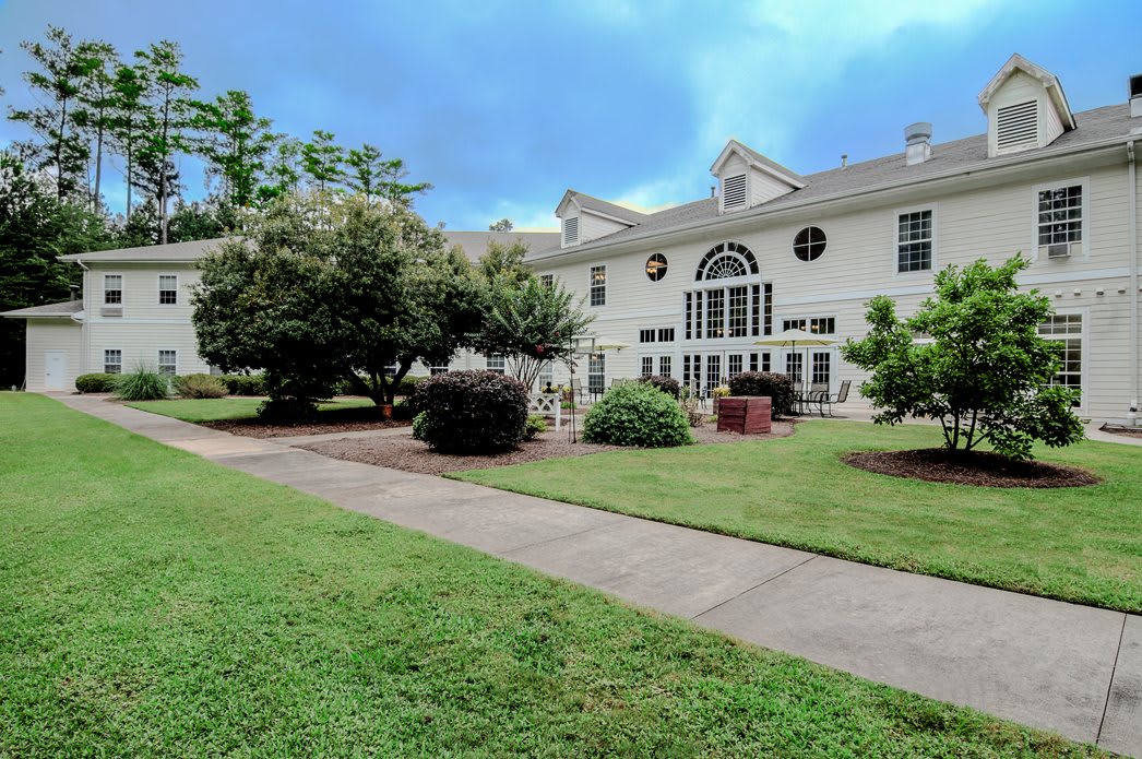 A large residential house with a well-maintained lawn and surrounding trees.