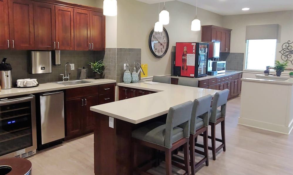 A modern kitchen interior featuring a central counter with bar stools and sleek appliances.