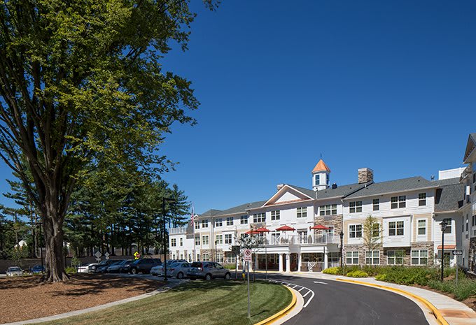 A residential building with multiple levels, surrounded by trees and under a clear blue sky.