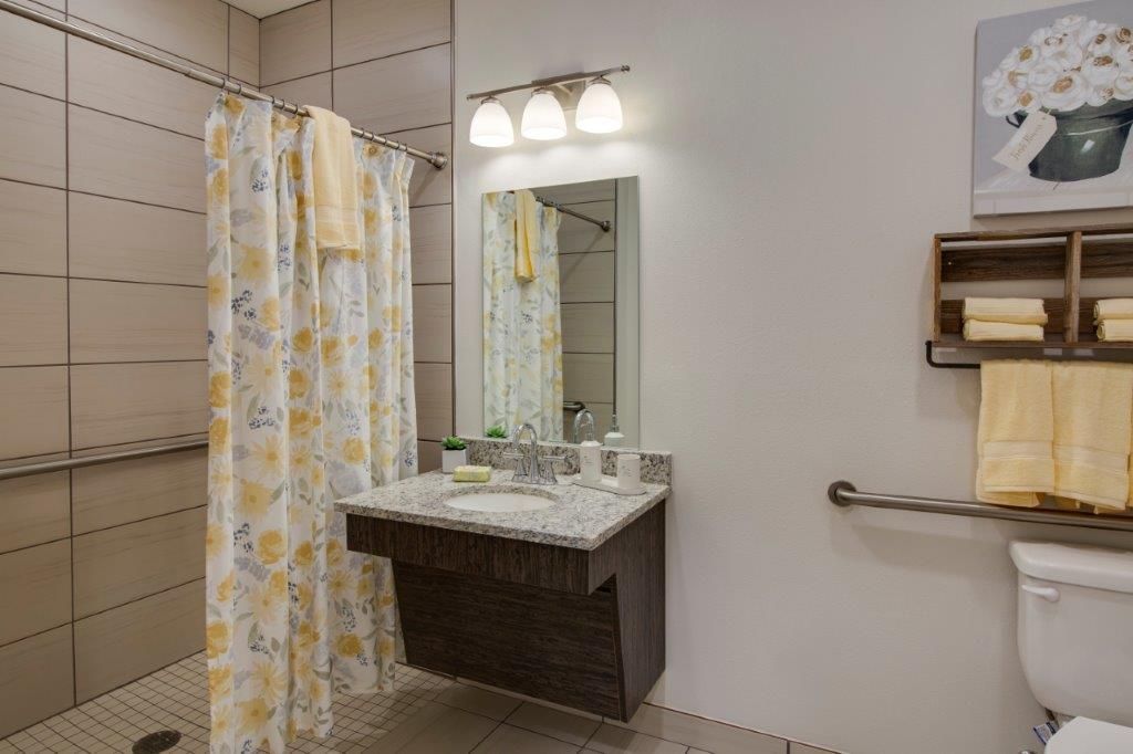 A modern bathroom with a sink, mirror, and shower area.