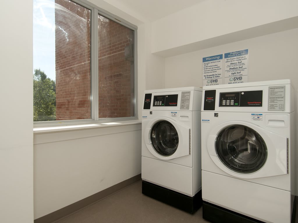A tidy laundry room with two modern washing machines next to a window.