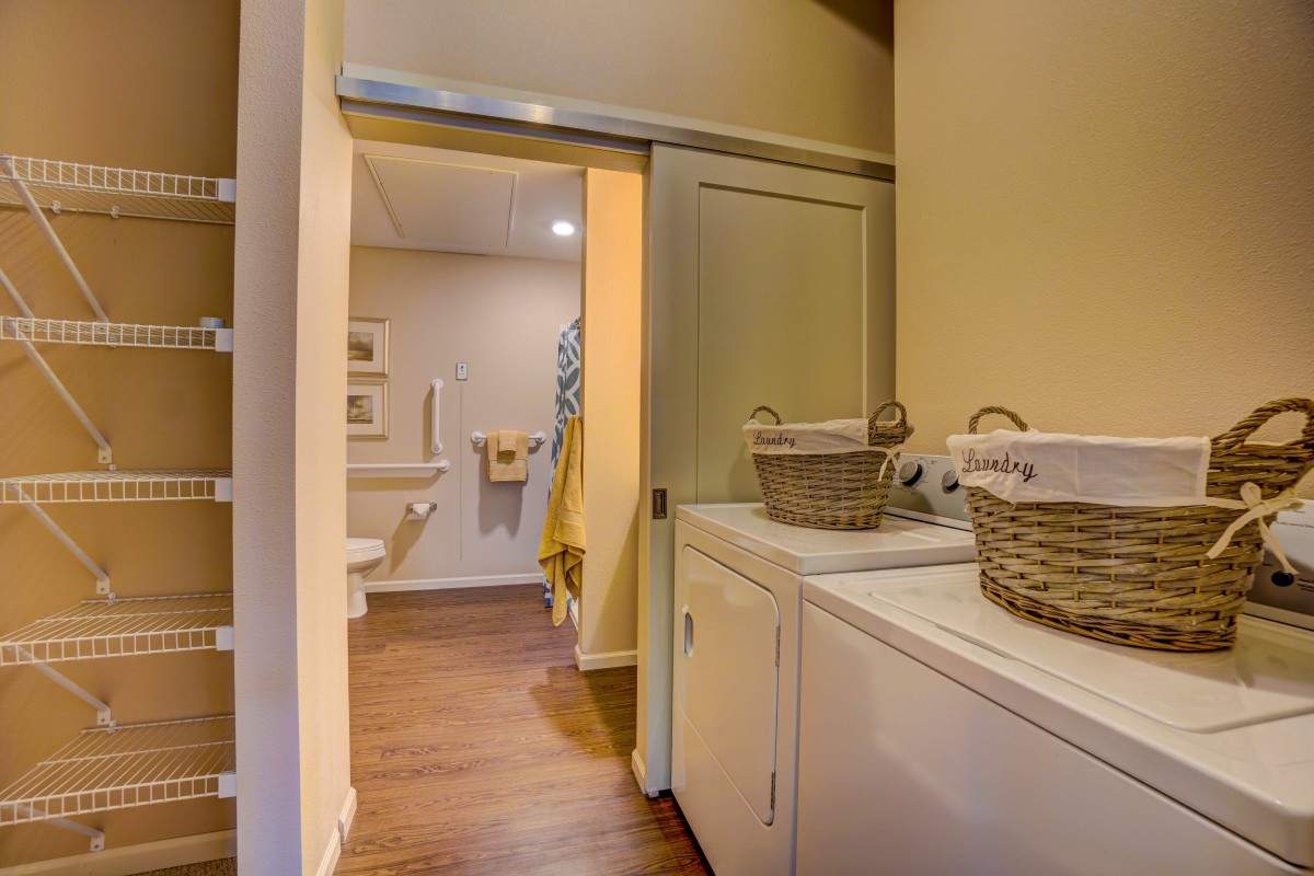 A cozy home interior featuring a laundry area with a washer and dryer, connected to a bathroom through a sliding door.