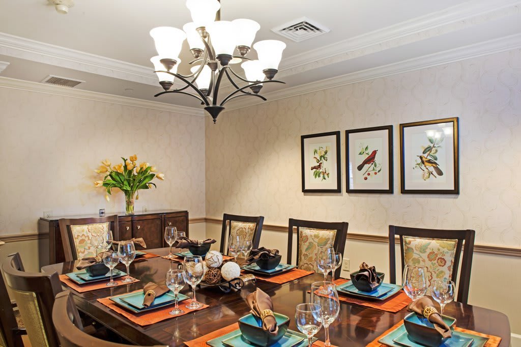 A beautifully arranged dining room with elegant table settings and a stylish chandelier.