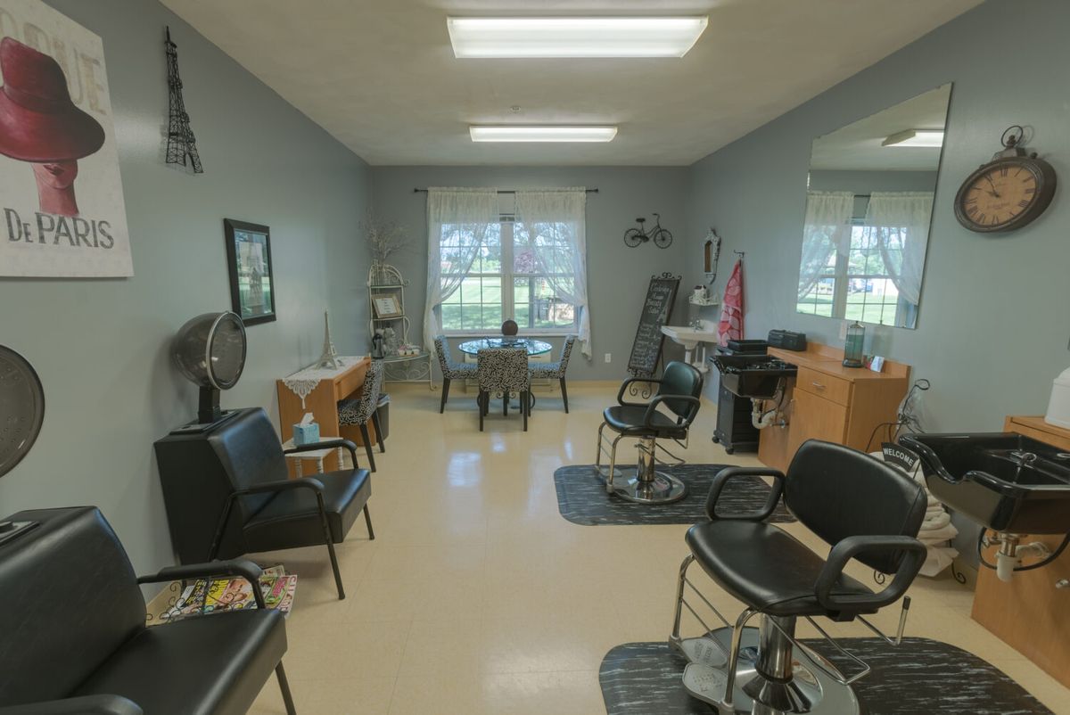 A modern hair salon featuring styling chairs and stations, with natural light entering through large windows.