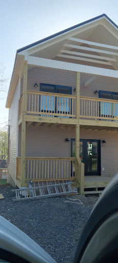 A modern two-story building featuring wooden balconies and a welcoming entrance.