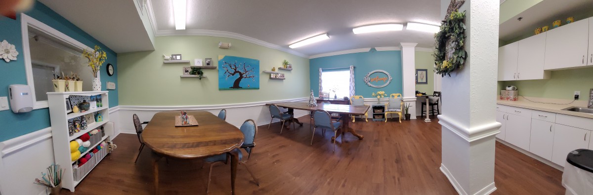 A cozy dining room with wooden floors, decorated with artwork and furnished with tables and chairs.